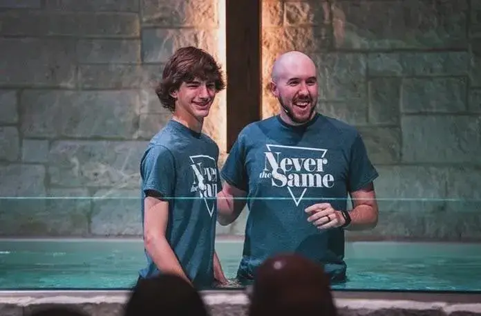 Young athlete being baptized by a youth pastor in a pool